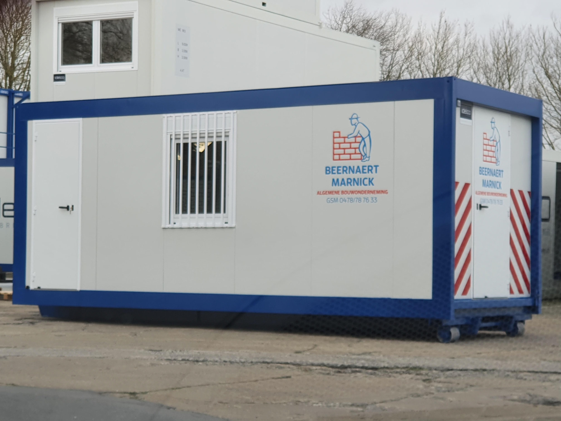 Verfahrbarer Idelco Baustellencontainer mit blauem Rahmen und Hakensystem auf einer Baustelle in Belgien